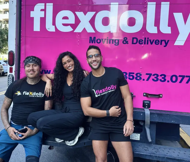 The Flexdolly crew sitting on the tailgate of a pink Flexdolly truck